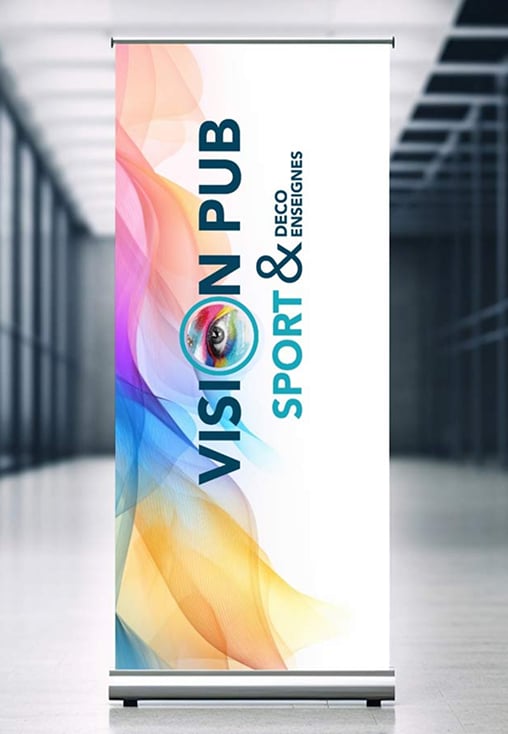 Roll-up publicitaire "VISION PUB" avec logo œil et "SPORT & DECO ENSEIGNES" sur fond coloré, exposé dans un intérieur moderne.
