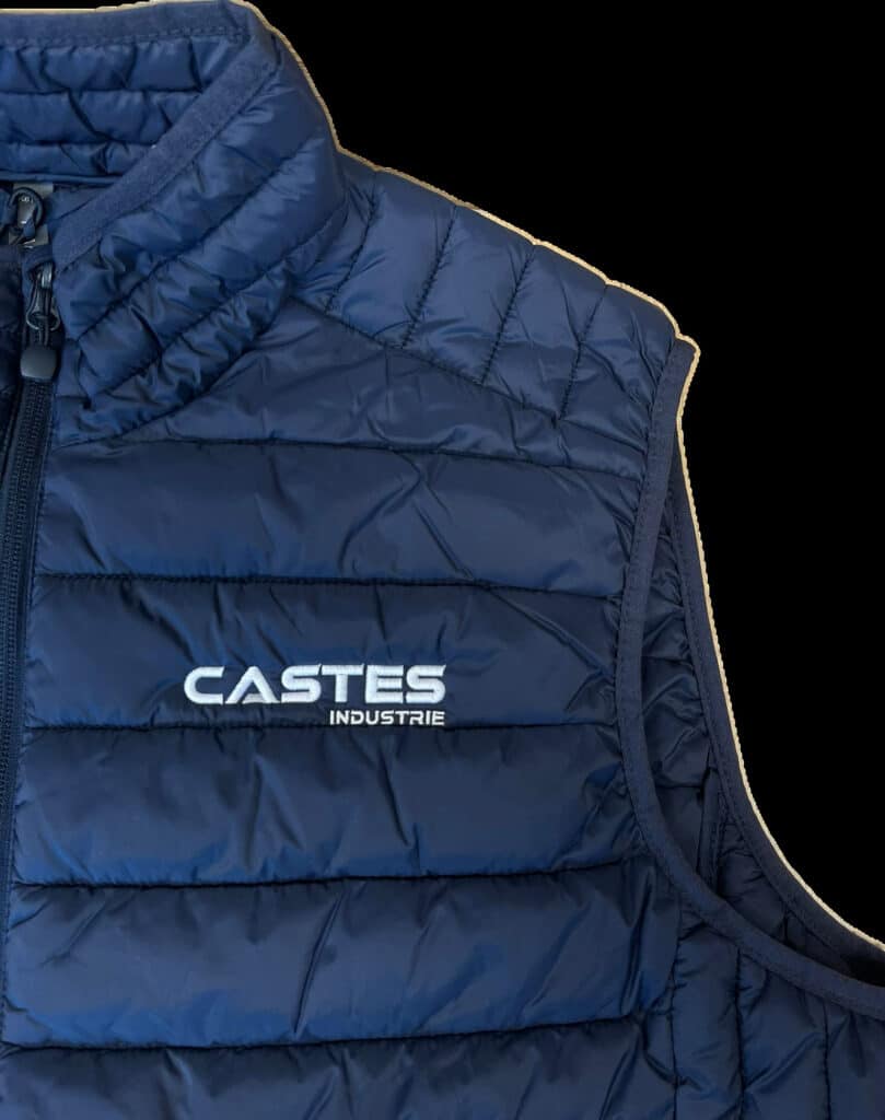 Gilet Doudoune Bleu CASTES INDUSTRIE avec Logo Gros plan sur un gilet matelassé bleu marine avec le logo blanc 'CASTES INDUSTRIE' imprimé sur la poitrine.